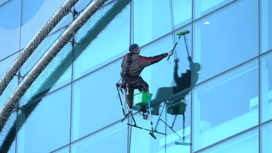 A man cleaning a glass window with a mop in grayscale, showcasing professional work.
